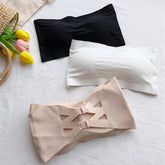 Three bras in black, white, and beige on a light surface with tulips and a basket.
